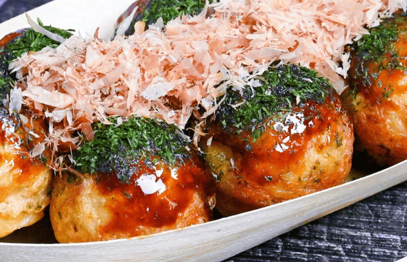 Crispy deep fried takoyaki served in a boat with sauce and bonito flakes in Singapore